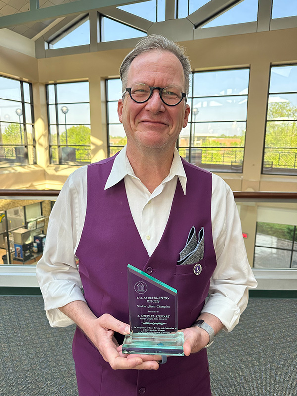 Dr. Michael Stewart holding his Student Affairs Champion award.